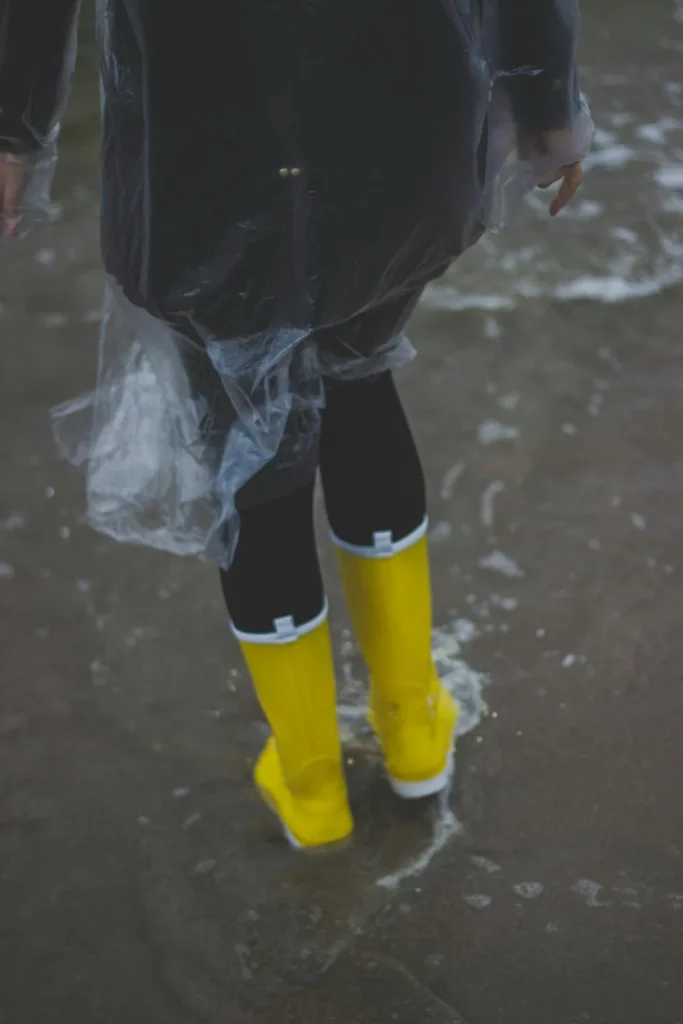 Person Wearing Clear Plastic Raincoat and Pair of Yellow Rainboots