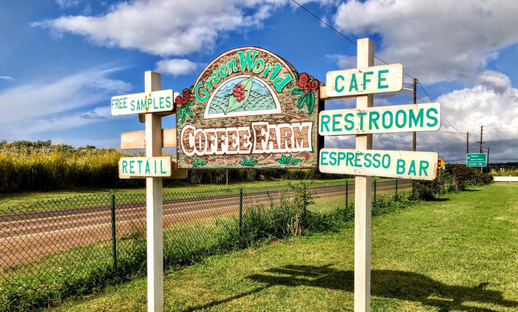 A 3D HDU Sign that says Green World Coffee Farm and next to directional signs that says Free samples, Retail, Cafe, Restrooms, and Espresso Bar located in Wahiawa, Hawaii.