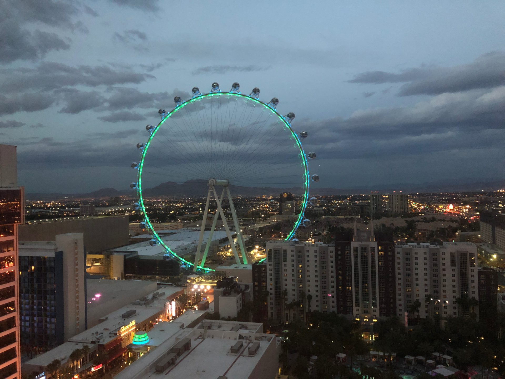 The High Roller Ferris Wheel at night is a towering structure decorated with vibrant LED lights and casting it's colorful reflections across the Las Vegas skyline.