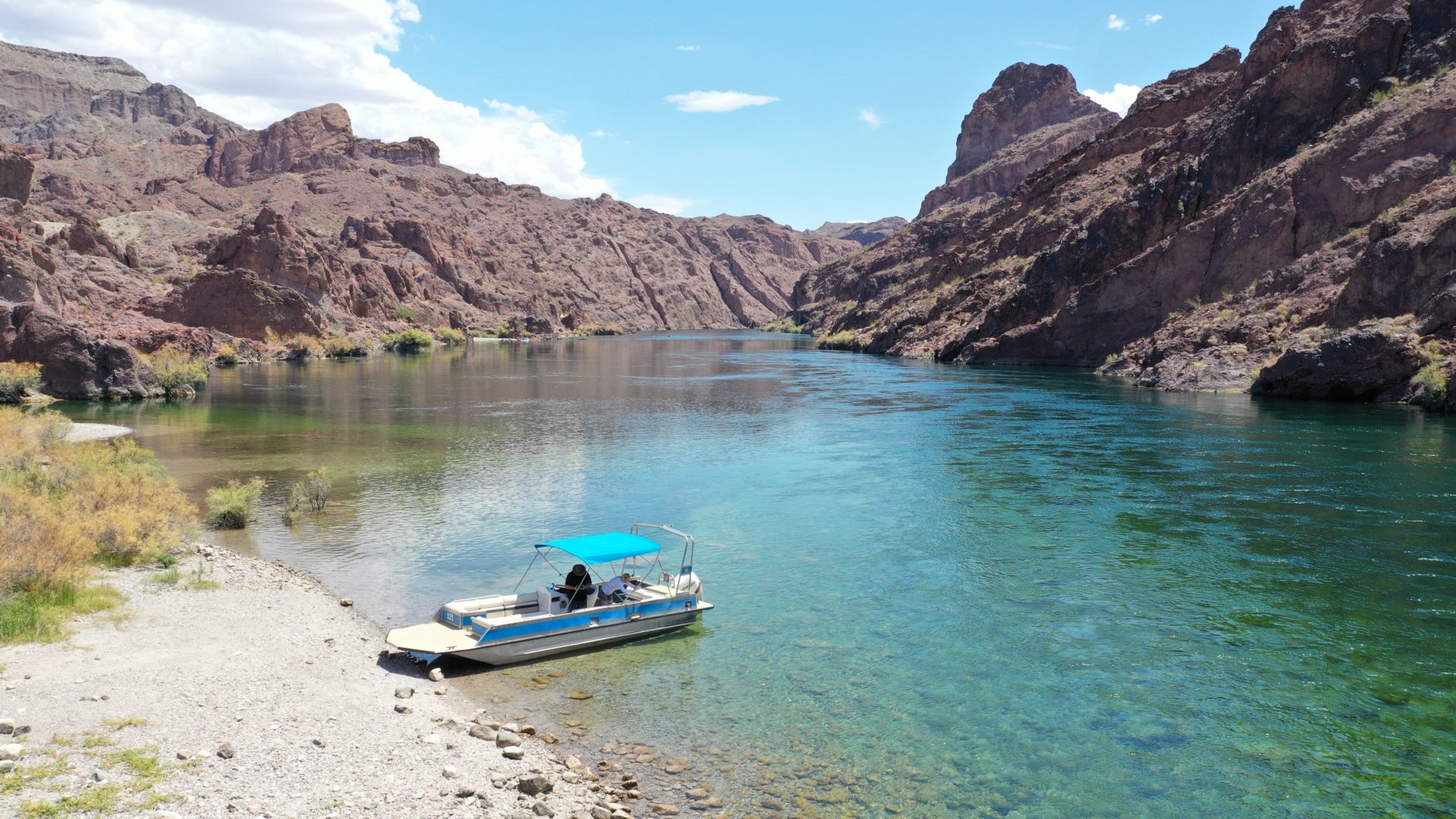 Lake Mead National Recreation Area features a body of water along the rugged desert landscapes and towering cliffs with a boat along the shore