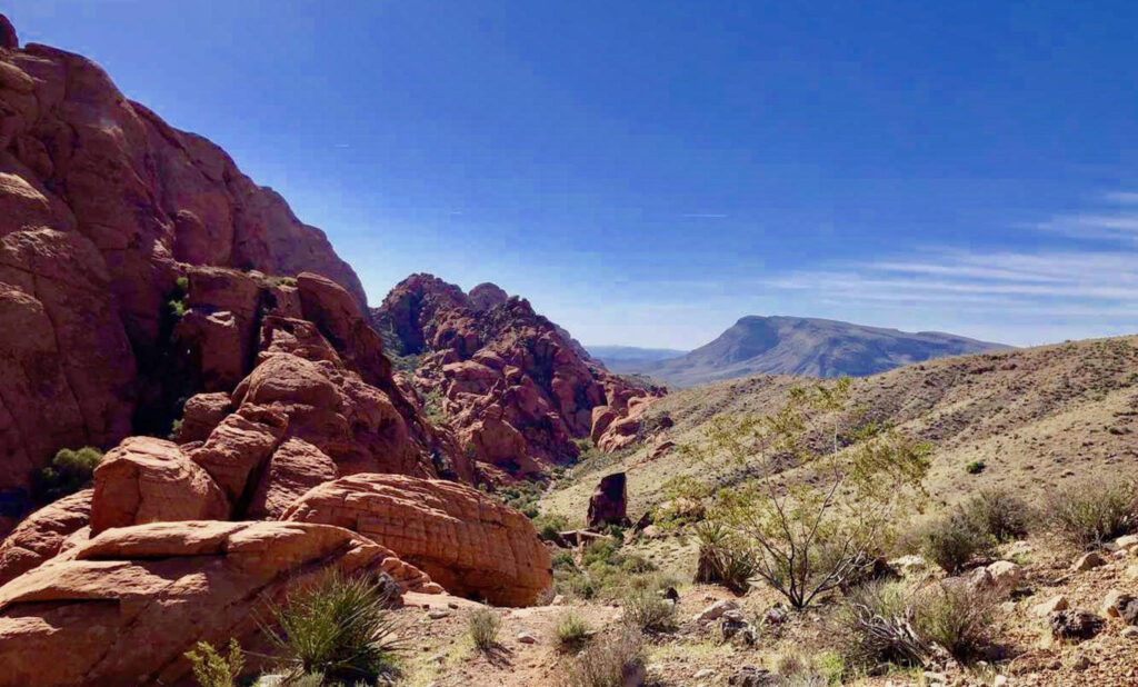 Red Rock Canyon National Conservation Area showcasing red sandstone formations and rugged desert terrain set against the backdrop of the Mojave Desert's expansive skies.