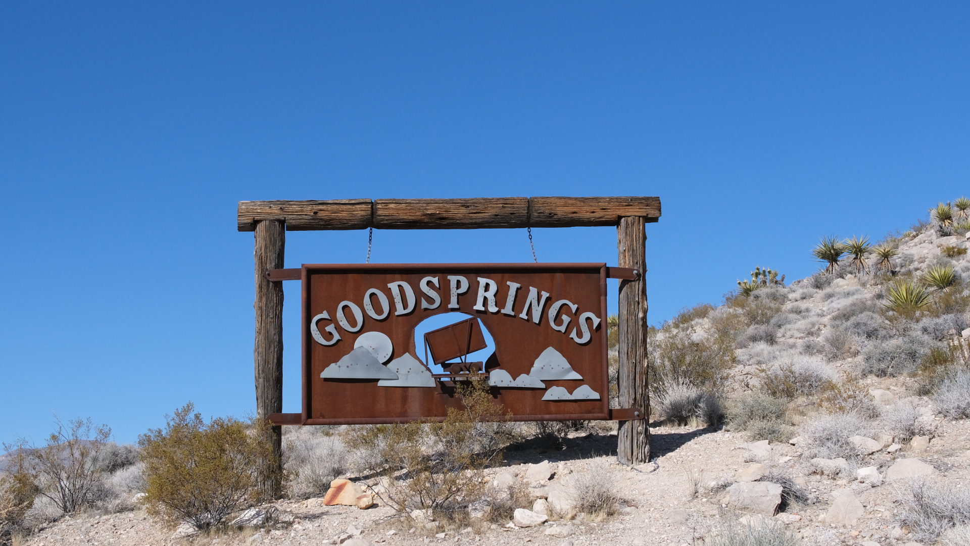 Near Las Vegas, Goodsprings involves historic buildings, dusty streets, and rugged desert surroundings, providing visitors a wooden 3D sign saying Goodsprings with cloudy mountain graphics
