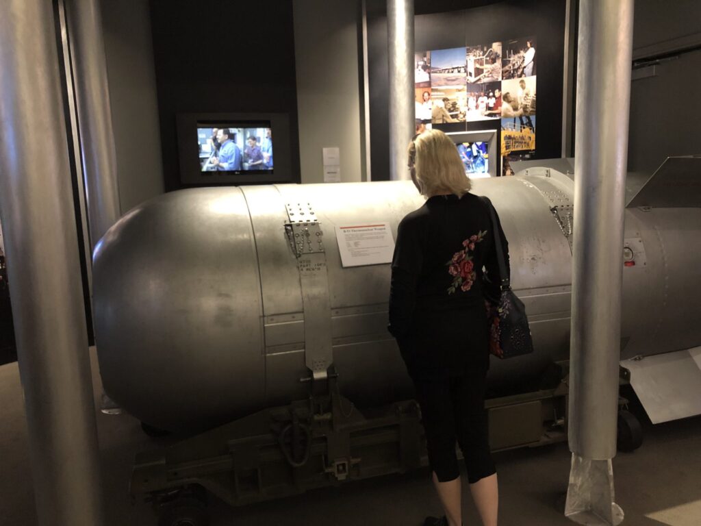 The National Atomic Testing Museum presents a display of an old fashion atomic bomb that exhibits into the history and impact of nuclear testing in the United States as a female viewer looks upon it