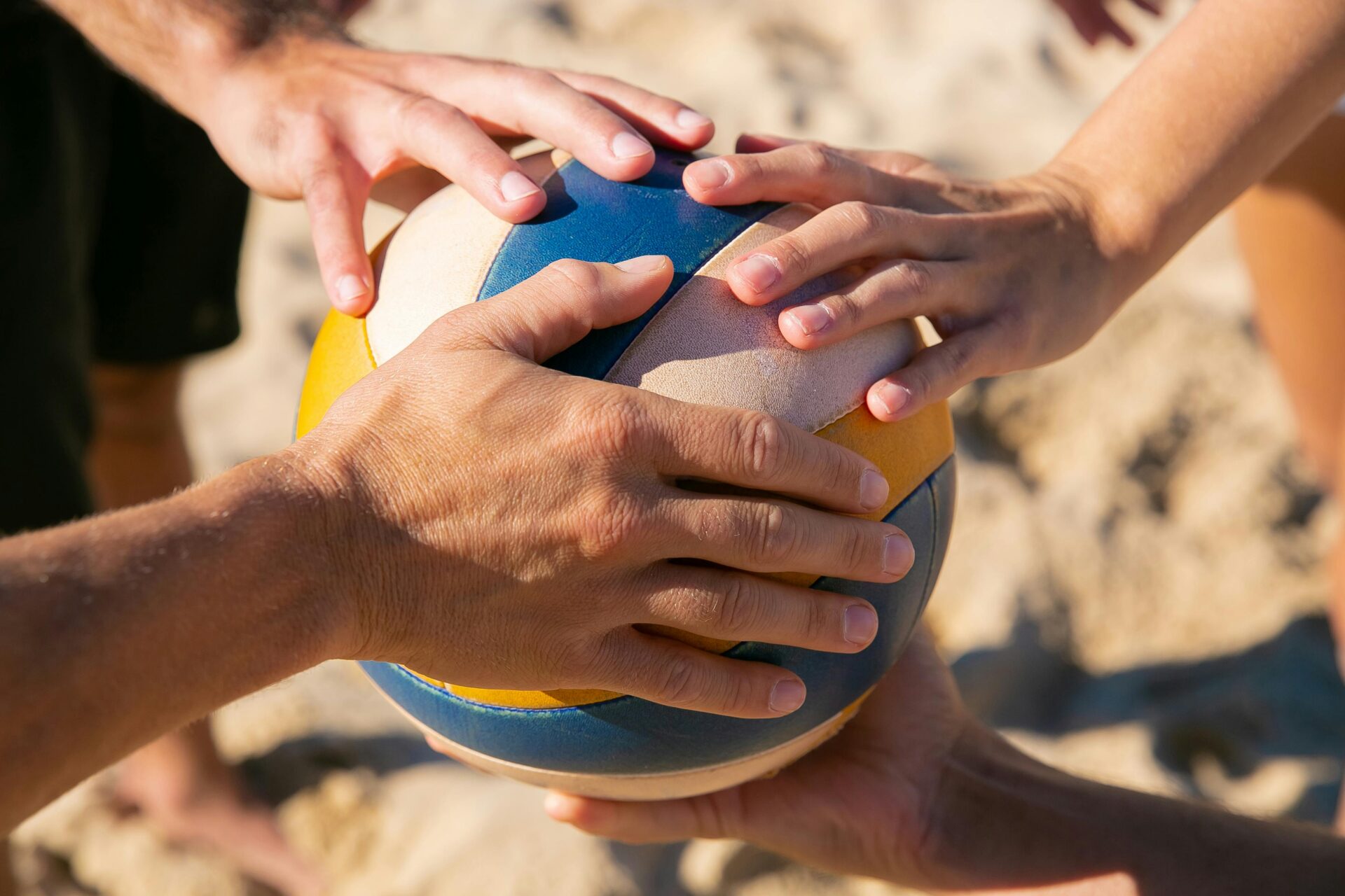 a volleyball with a few hands on it, ready to play at the olympics